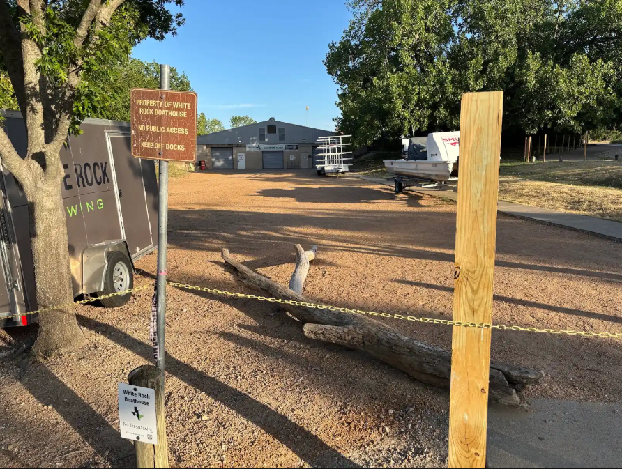Fence posts and a sign saying "Property of White Rock Rowing" stand outside White Rock Boathouse.