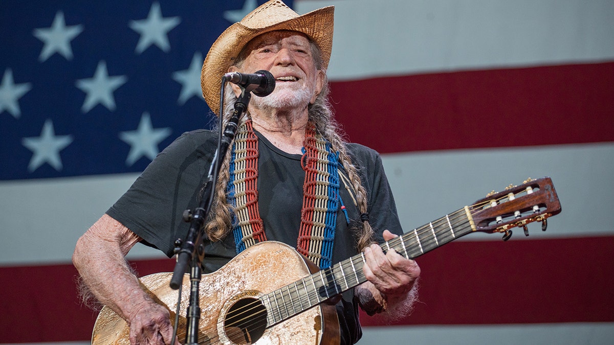 Willy Nelson plays guitar and sings