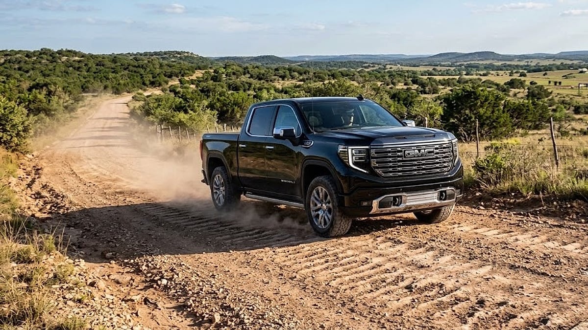 A black 2026 GMC Sierra Denali kicks up dust while kicking over rugged washboard dirt roads in rural Texas
