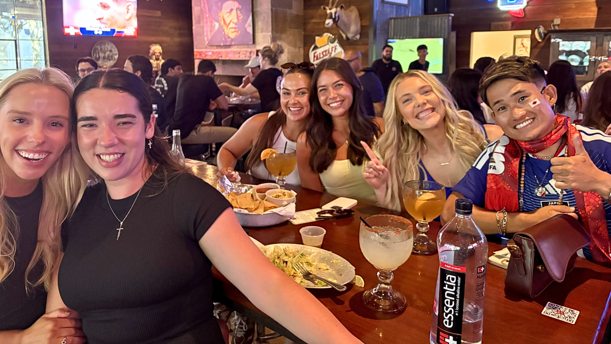 Japanese soccer fan on right hand side poses for a selfie with girls at a bar in Dallas during a World Cup game.