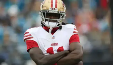 Brandon Aiyuk stands with his arms crossed while wearing the San Francisco 49ers’ white uniform and gold helmet.