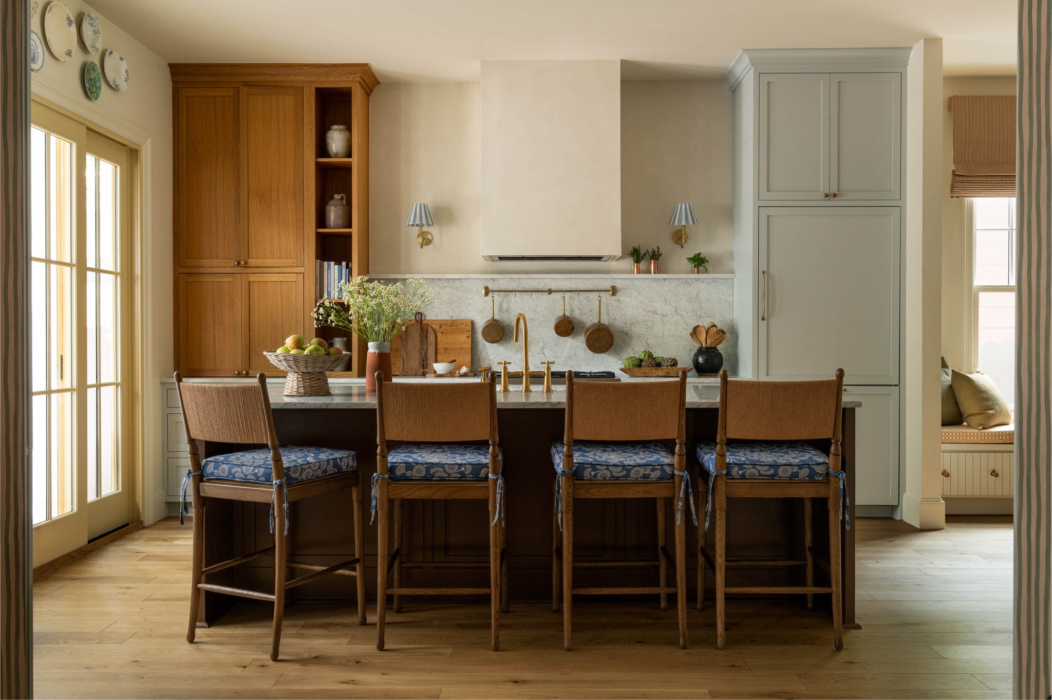A modern kitchen featuring wood cabinetry, marble countertops, and seating at a central island with decorative elements.