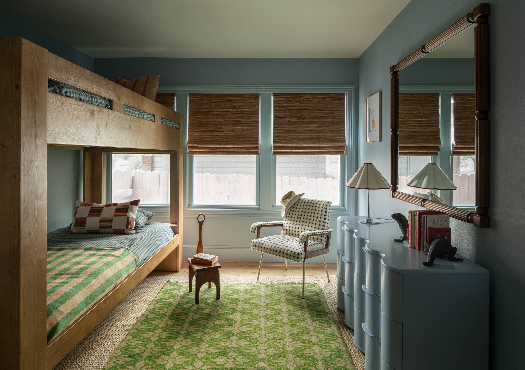 Brightly decorated bedroom featuring a bunk bed, patterned rug, and modern furnishings with natural light from windows.