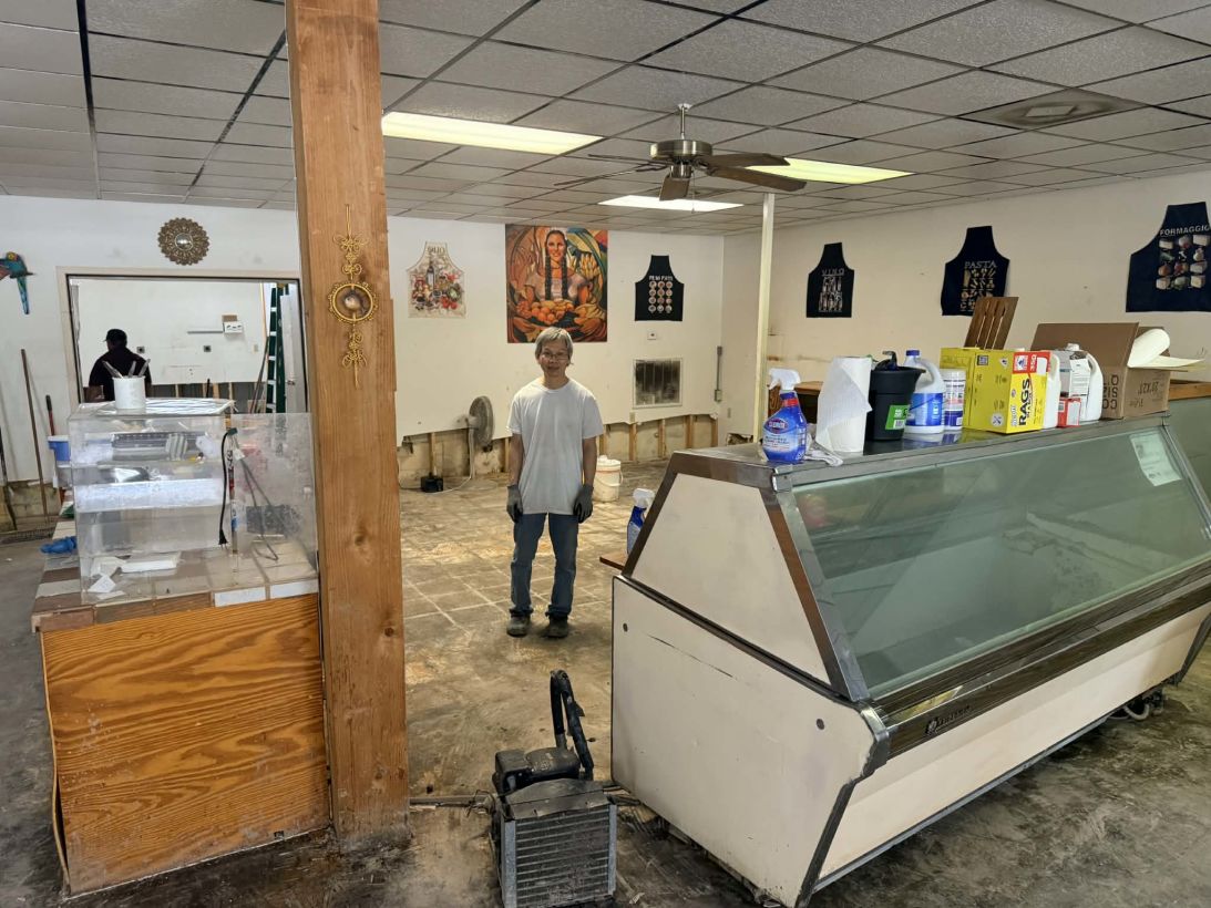 Chong Chin standing in the middle of his deli, after neighbors and friends rallied to help him clean up after floods destroyed his store and home.