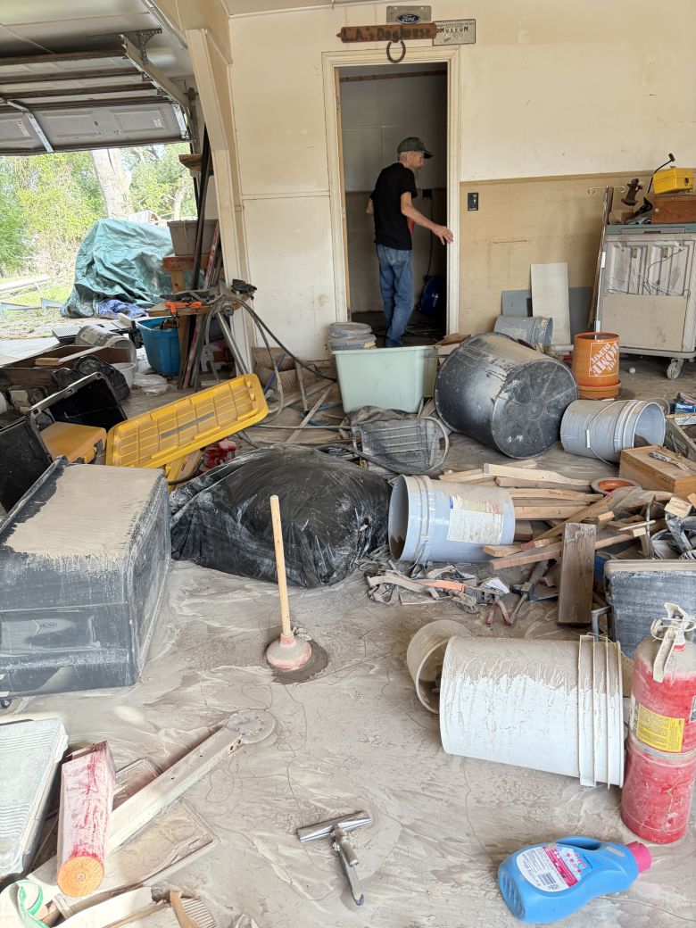 Volunteers have been visiting Cude, pictured in his garage, to help him clean up his damaged home.