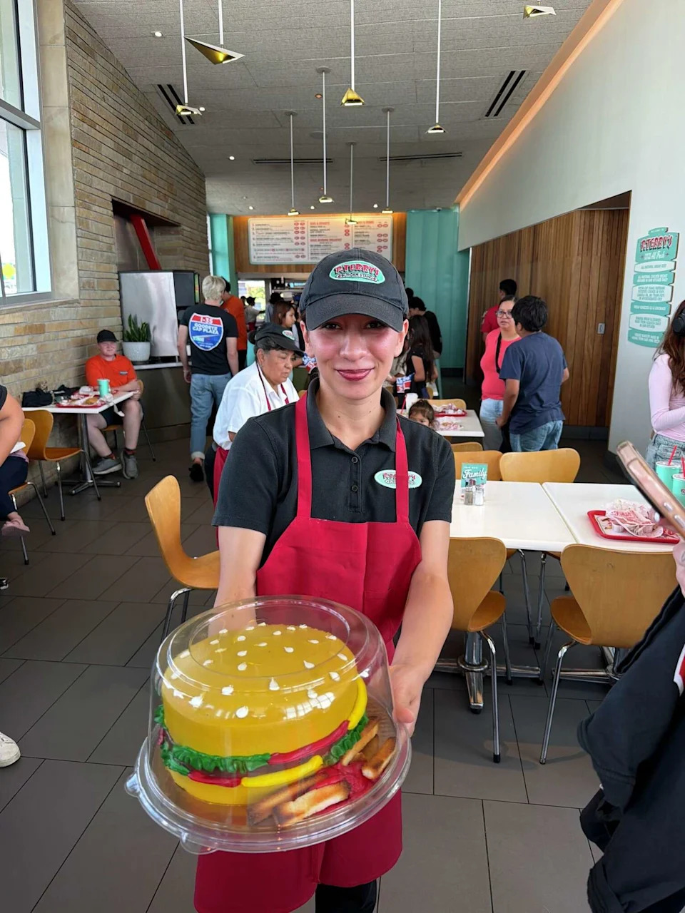 A P. Terry's employee holds up a burger cake at the chain's farewell celebration for its Capital Plaza off of Interstate 35 in Austin on Friday, June 26. (Devon Messinger/Courtesy of P. Terry's)