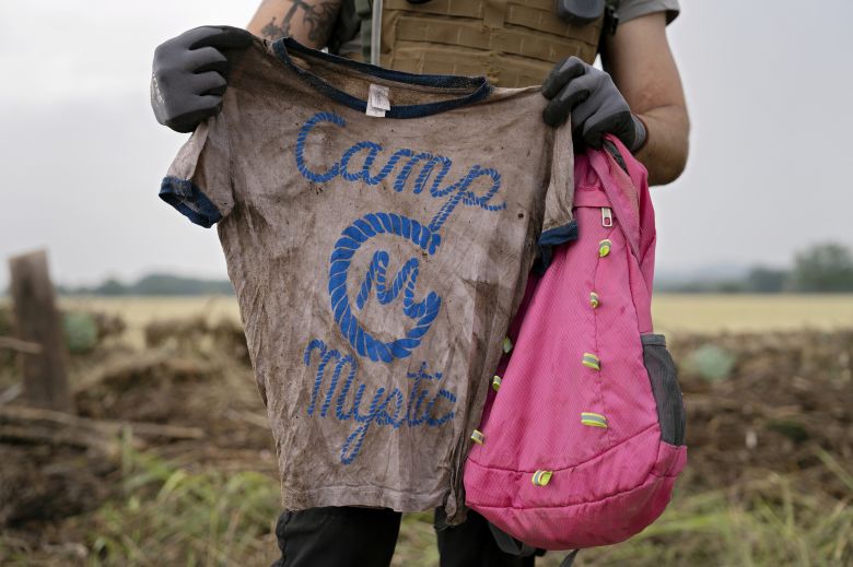 A search and rescue volunteer holds a T-shirt and backpack with the words Camp Mystic on them in Comfort, Texas on July 6, 2025.
