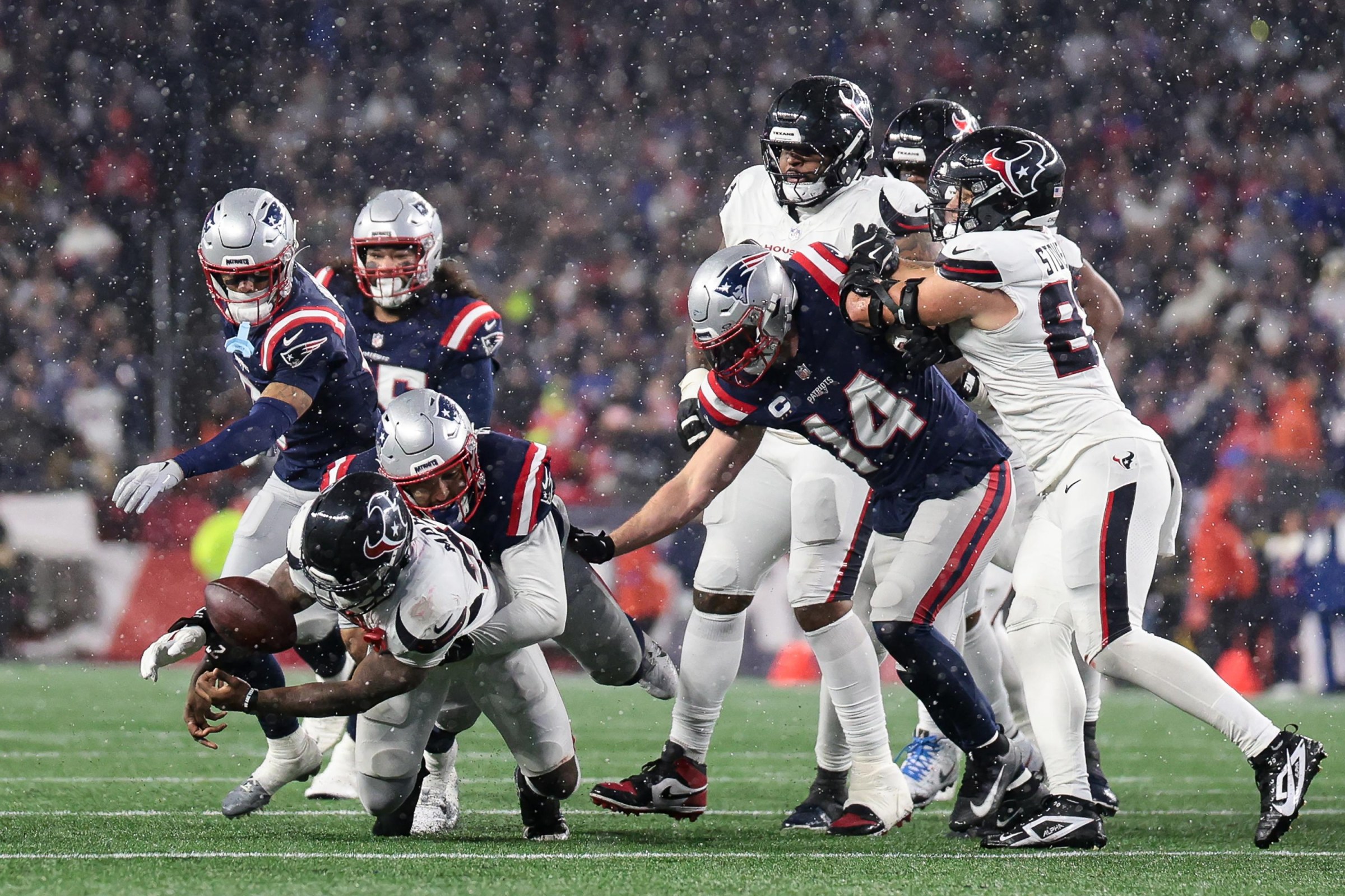 FOXBOROUGH, MASSACHUSETTS - JANUARY 18: Woody Marks #27 of the Houston Texans fumbles the ball after a tackle by Christian Gonzalez #0 of the New England Patriots in the second half during an AFC Divisional Playoff game at Gillette Stadium on January 18, 2026 in Foxborough, Massachusetts. (Photo by Kathryn Riley/Getty Images)