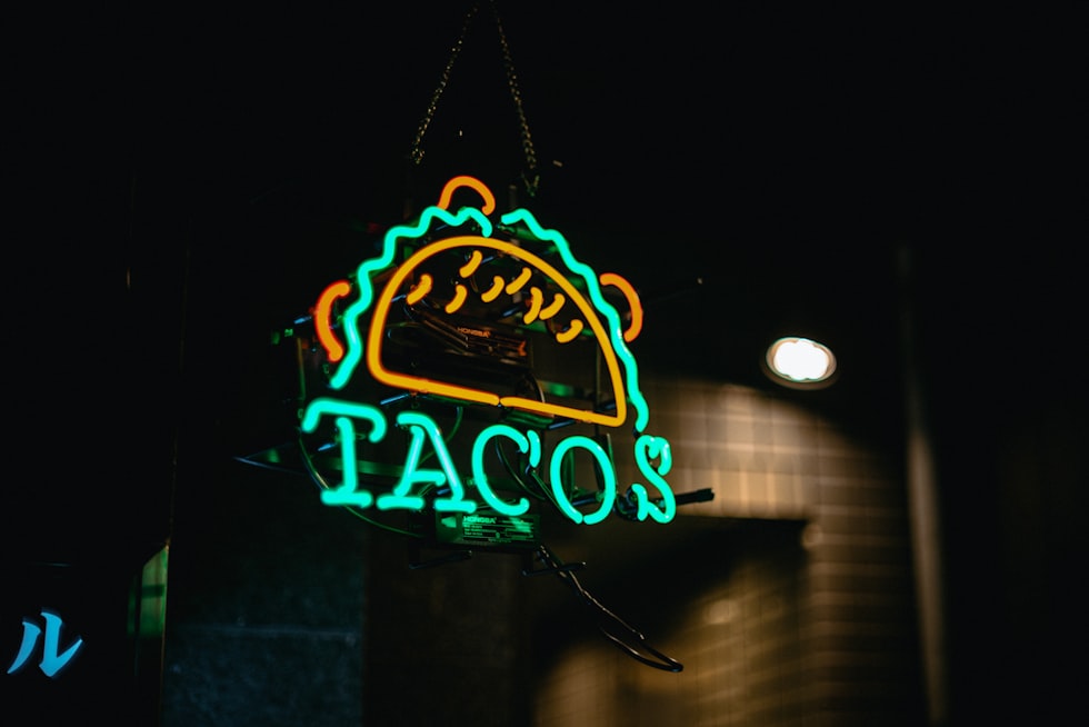 A neon sign advertising tacos at night