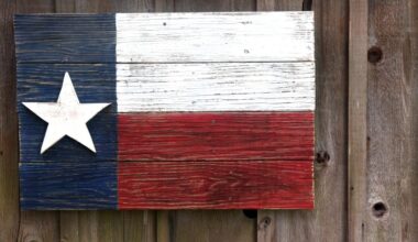 A Texas flag painted on very old boards and hanging on a barn.