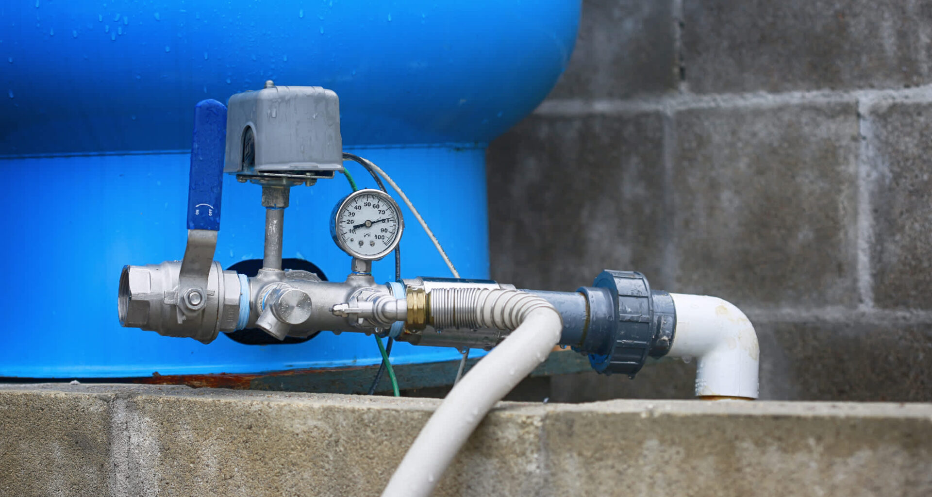A water pump system with a pressure gauge and blue tank.