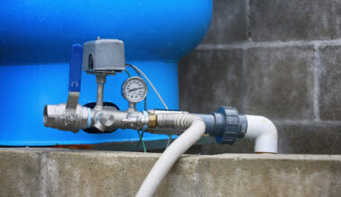 A water pump system with a pressure gauge and blue tank.