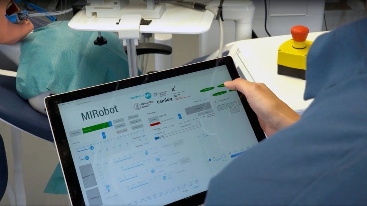 A person monitors the dental robot with a monitor.