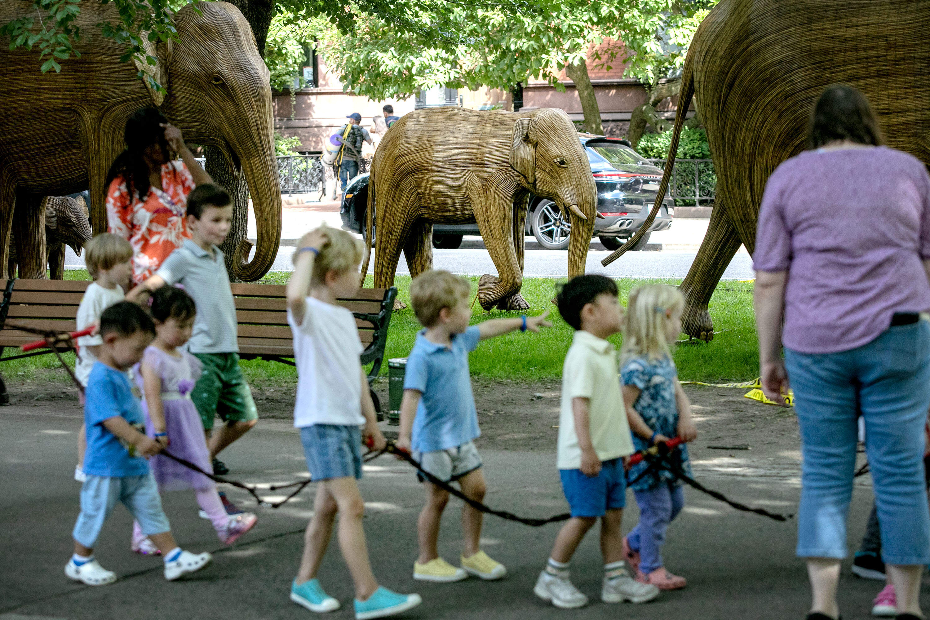 Children walk along Commonwealth Avenue Mall in Boston, near a sculpture of a young elephant in "The Great Elephant Migration" installation. (Robin Lubbock/WBUR)