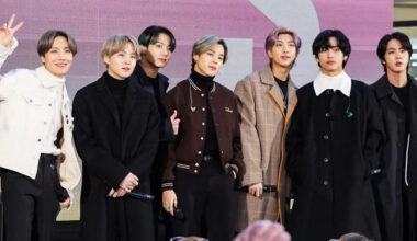 BTS, the K-pop band, stands together. One member throws a peace sign.
