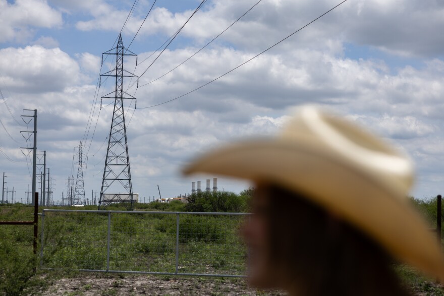 Transmission lines stretch towards the horizon while an out of focus person's head wearing a cowboy hat is in the foreground.
