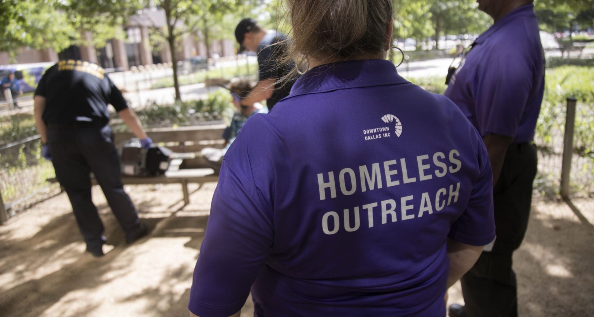 From left, Street outreach workers with Downtown Dallas, Inc. Leia Reneau and Charles Davis watch as paramedics speak to a men they discovered needed medical attention while talking to people at Civic Garden on Wednesday, May 15, 2024, in downtown Dallas.