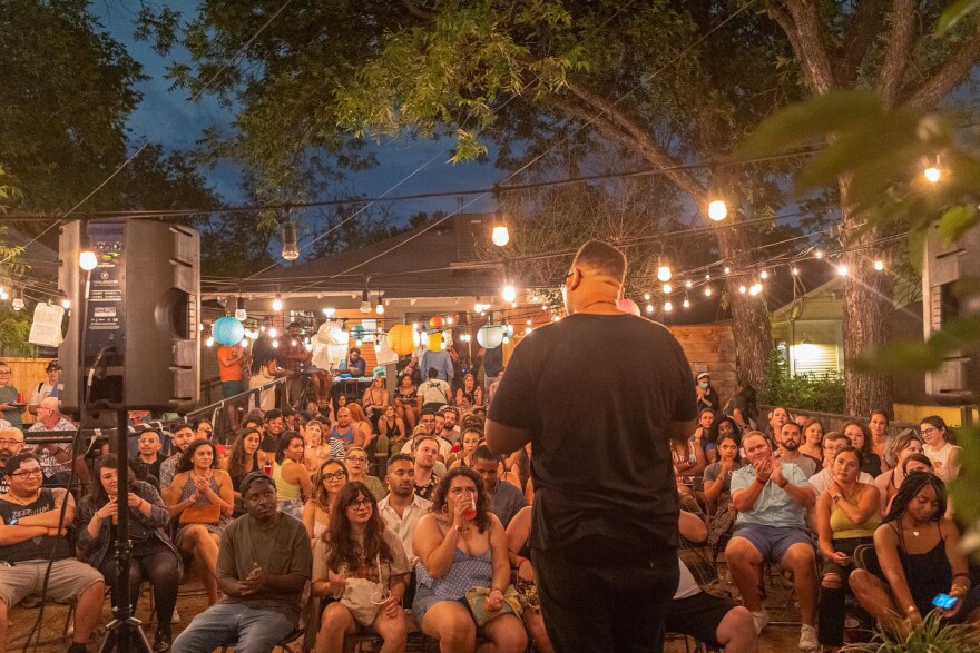 Event creator and host faces an engaged crowd in the outdoor space of The Wild Detectives bookstore in Oak Cliff