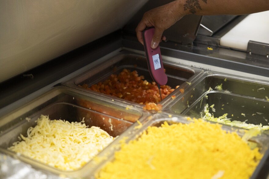 A thermometer measures food temperatures in various steel bins.