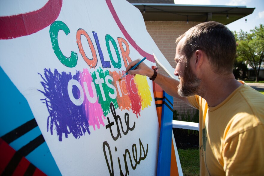A man paints a giant adirondack chair.