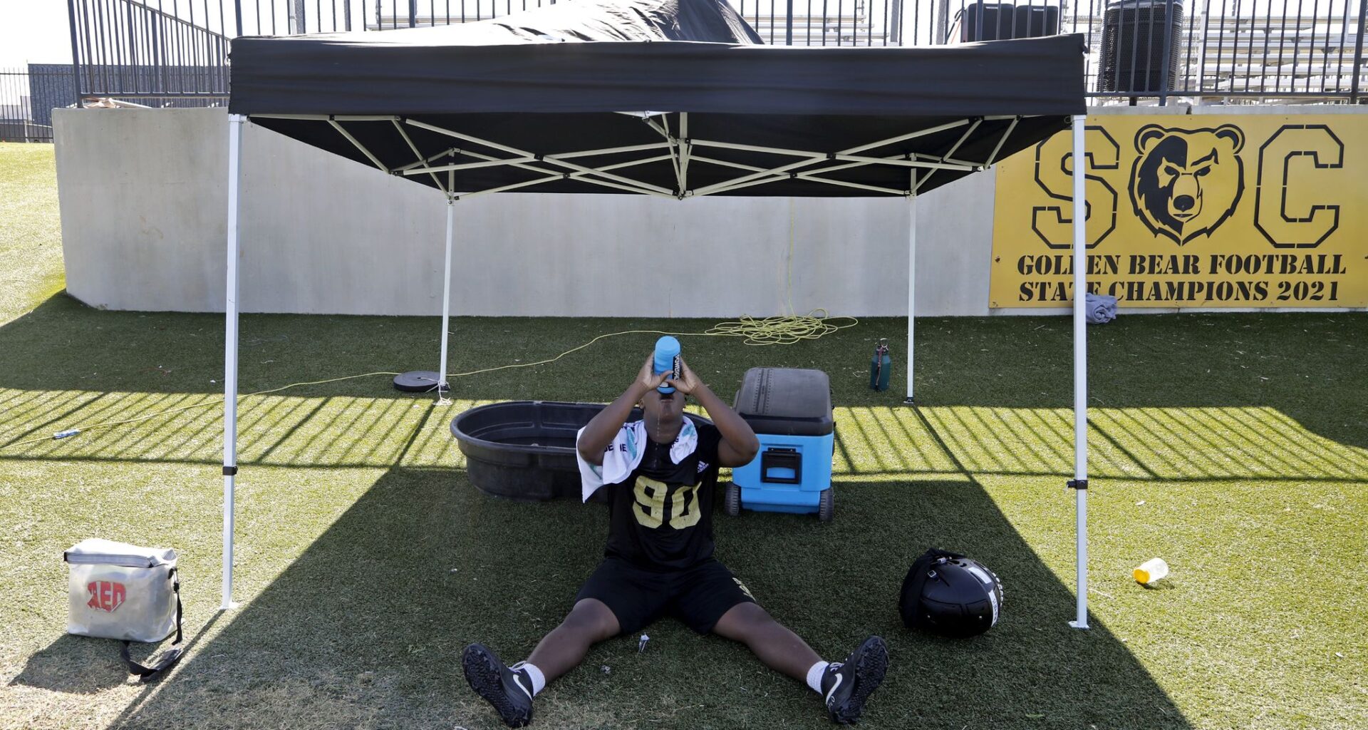 DeAngelo ;Mathis, 16, of Dallas, drinks water in the shade while temperatures heated up as South Oak Cliff High School held their first day of football practice on Monday morning, August 10, 2026.