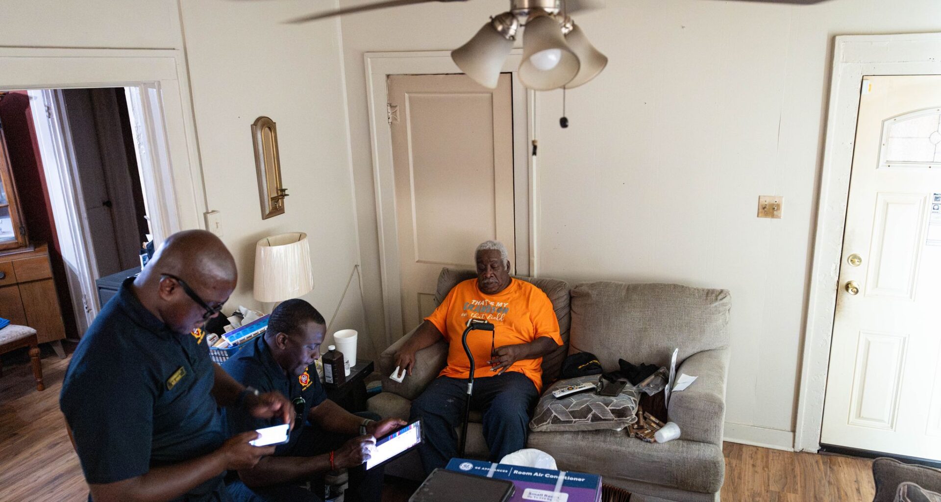 Dallas Fire Rescue Firefighter Paramedics Rickey Giles, left, and Brandon Asberry ask resident James Epps, 77, questions after bringing a window AC unit, provided by The Senior Source, to his home in Dallas, Wednesday, Aug. 5, 2026.