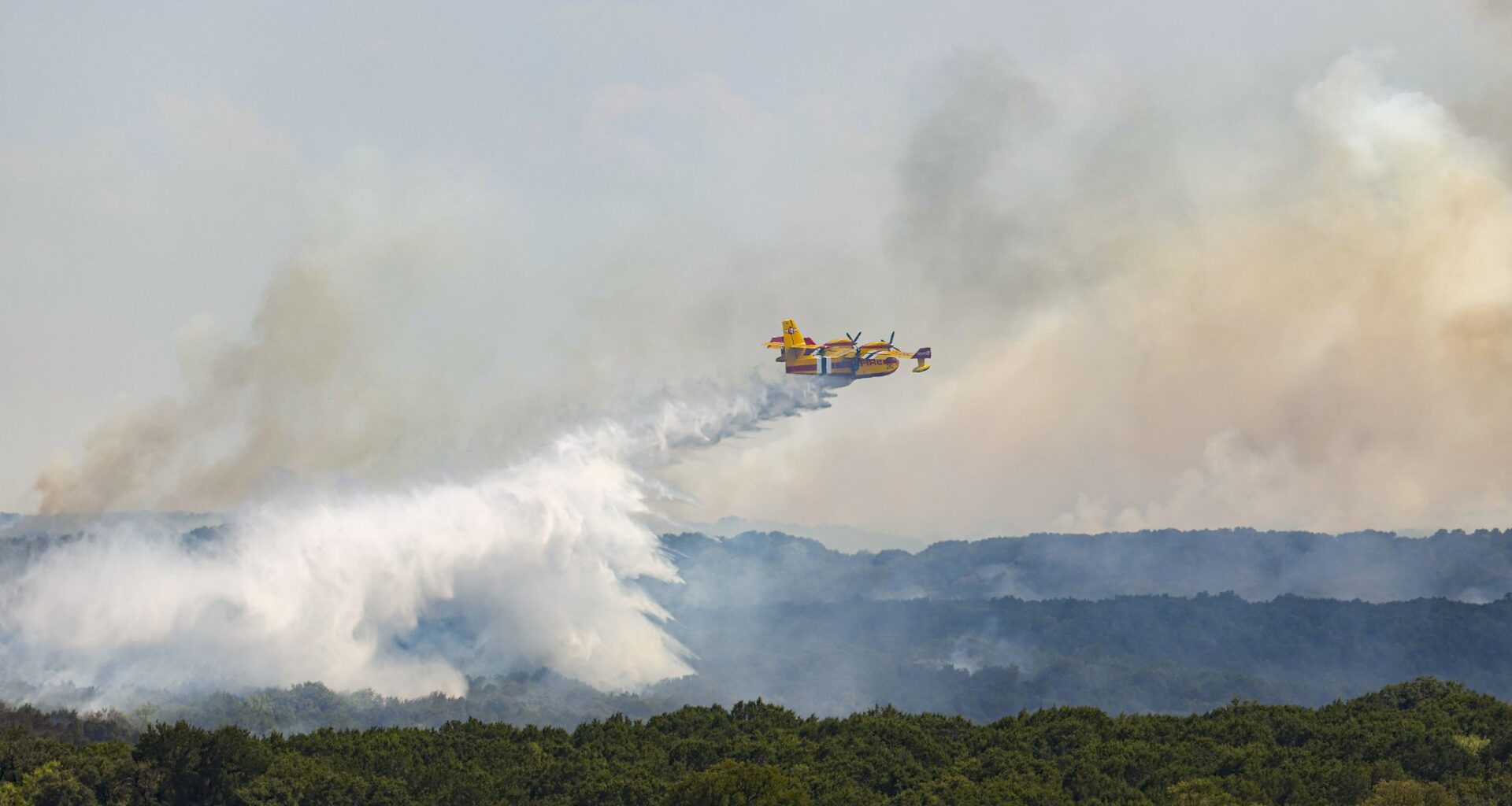 A 'Super Scooper' plane drops water on the Ross fire spreading across the ridge, on Friday, Aug. 28, 2026 in Palo Pinto County.