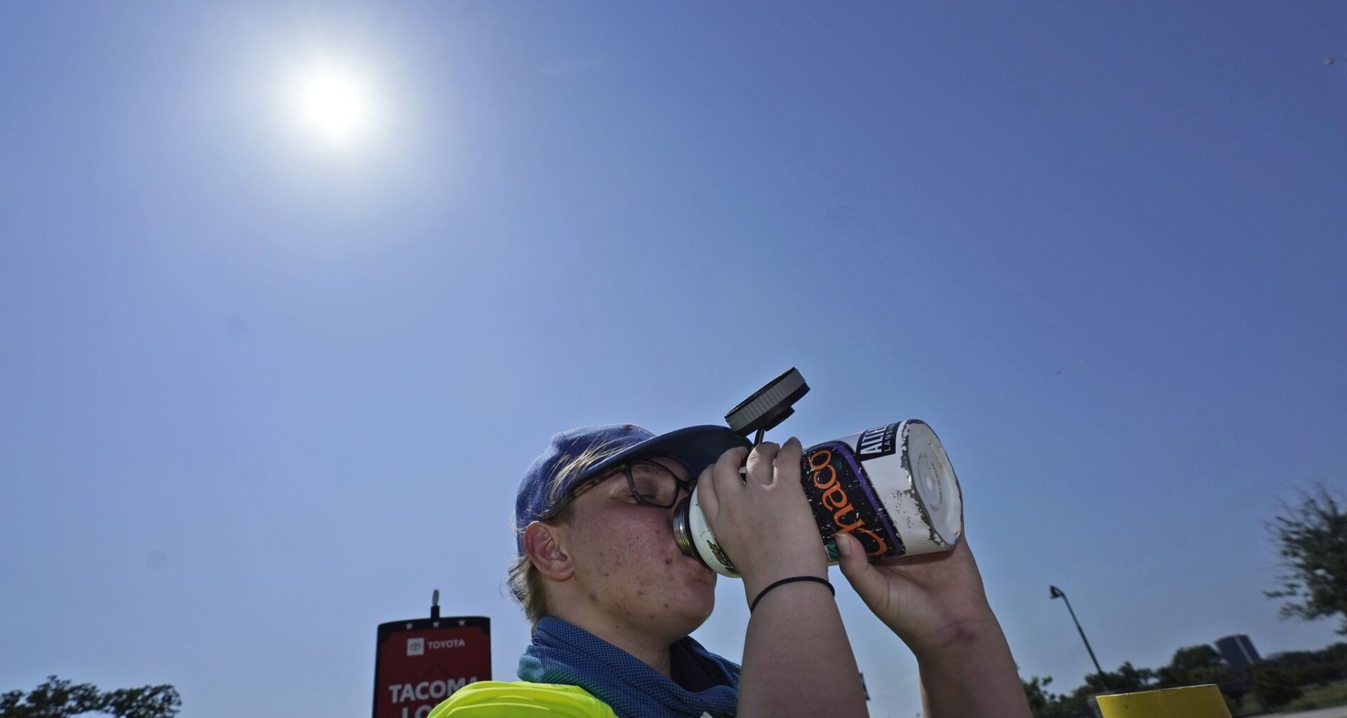 Jennifer Michener drinks water while working in the hot sun in a parking lot in Arlington, Texas, Monday, June 26, 2023. (AP Photo/LM Otero)
