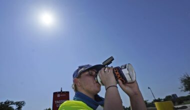 Jennifer Michener drinks water while working in the hot sun in a parking lot in Arlington, Texas, Monday, June 26, 2023. (AP Photo/LM Otero)