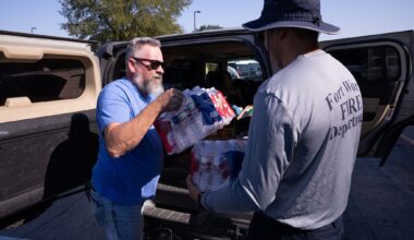 Marty Goin hands donated water to Fort Worth Firefighter/EMT Elfidio Quiñónez as the Fort Worth Police Department South Division hosts a supply drive in Fort Worth, Saturday, Aug. 29, 2026. The department collected donations to support the firefighters working to battle the Ross fire.