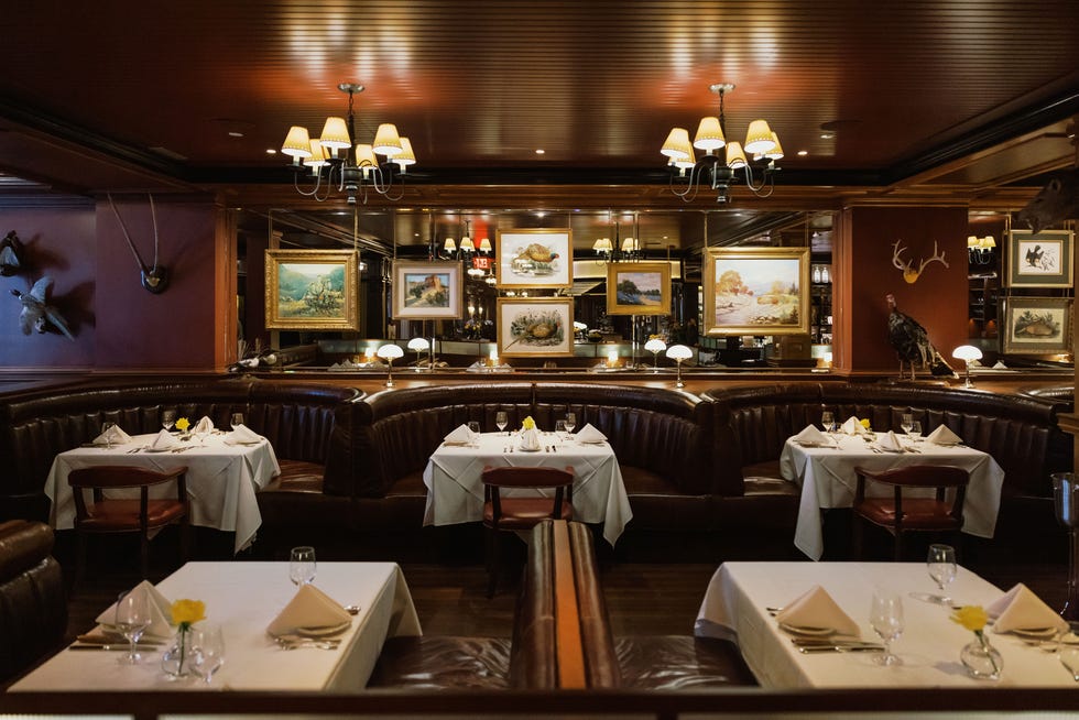 Elegant restaurant interior with leather seating, tables set for dining, and decorative artwork on the walls.