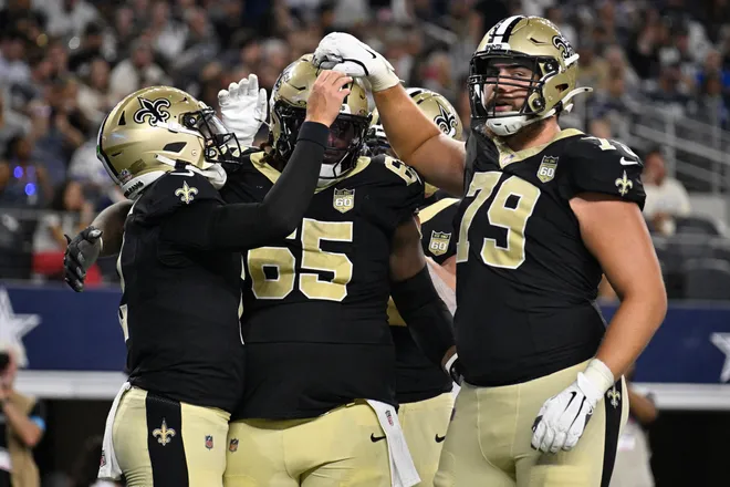 Aug 28, 2026; Arlington, Texas, USA; New Orleans Saints quarterback Spencer Rattler (2) celebrates with guard Jeremiah Wright (65) and offensive line Alex Wollschlaeger (79) after scoring a touchdown against the Dallas Cowboys during the second quarter at AT & T Stadium. Mandatory Credit: Jerome Miron-Imagn Images