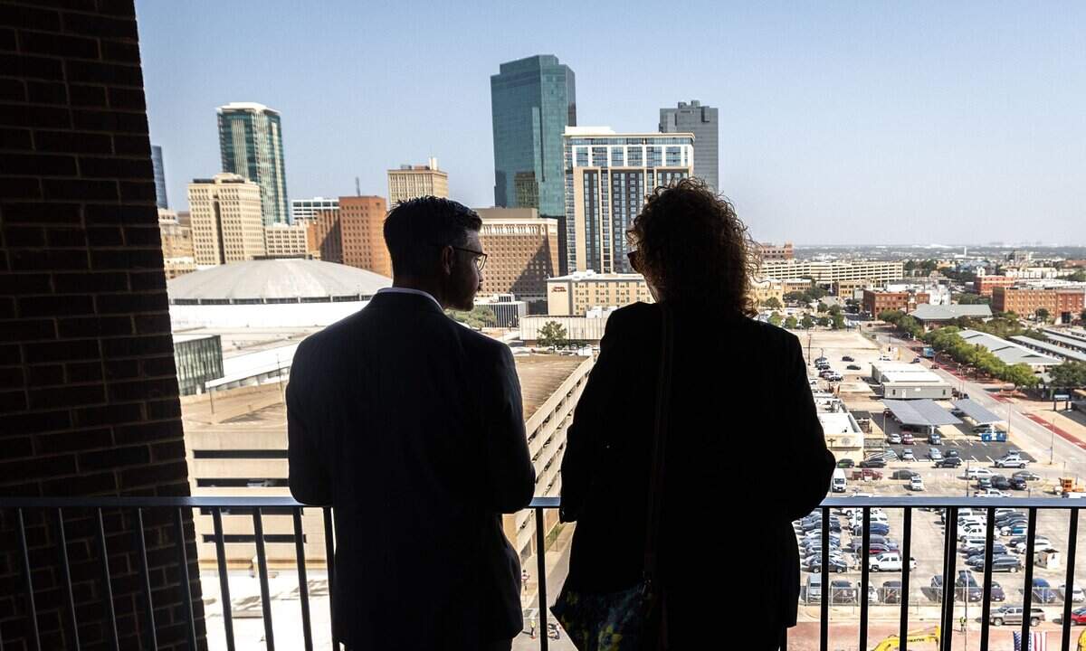 Attendees talk outside on a balcony in the Texas A&M Law and Education Building during its grand opening in Fort Worth on Aug. 5, 2026.