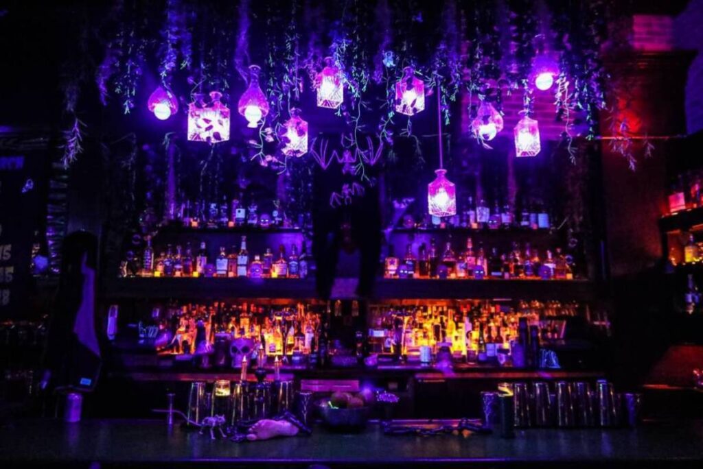 Image shows the interior of a bar during the Black Lagoon pop-up featuring decor and moody lighting fixtures.
