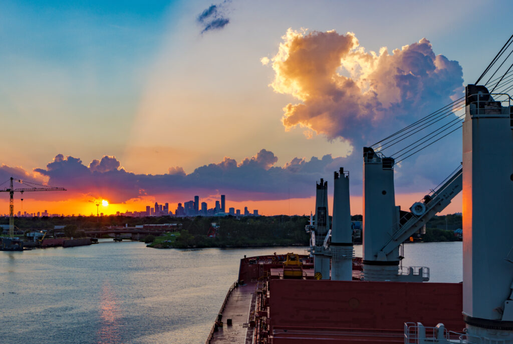 Image shows a boat cruising in the Port of Houston with the city skyline in the background.