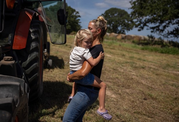 Mandy Williams holds onto her daughter Violet as she gets out of a hay harvester in Centerville. (Antranik Tavitian/For The Washington Post)