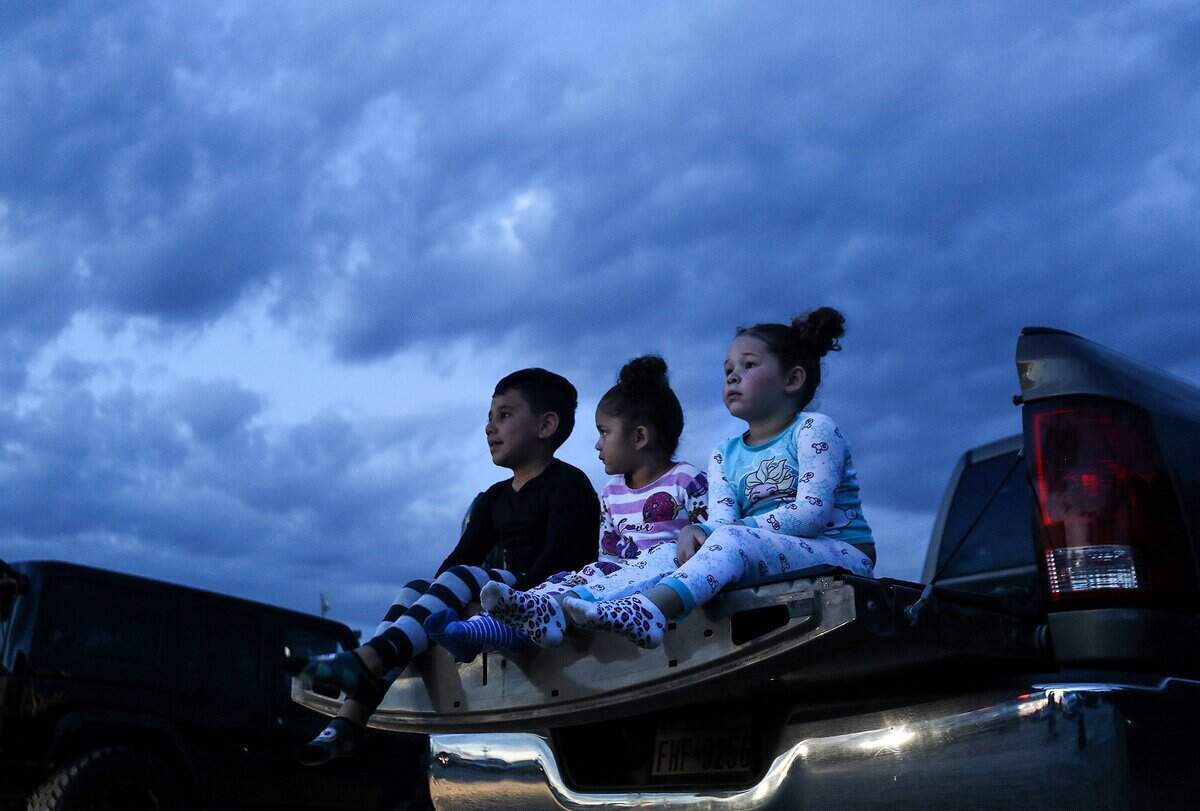 Julian Dominguez, 6, left, Bryleigh Brown, 3, center, and Brooklyn Brown, 5, sit in the back of a pickup in their pajamas to watch a movie with their family at Coyote Drive-In movie theater on Wednesday, May 27, 2020, in Fort Worth.