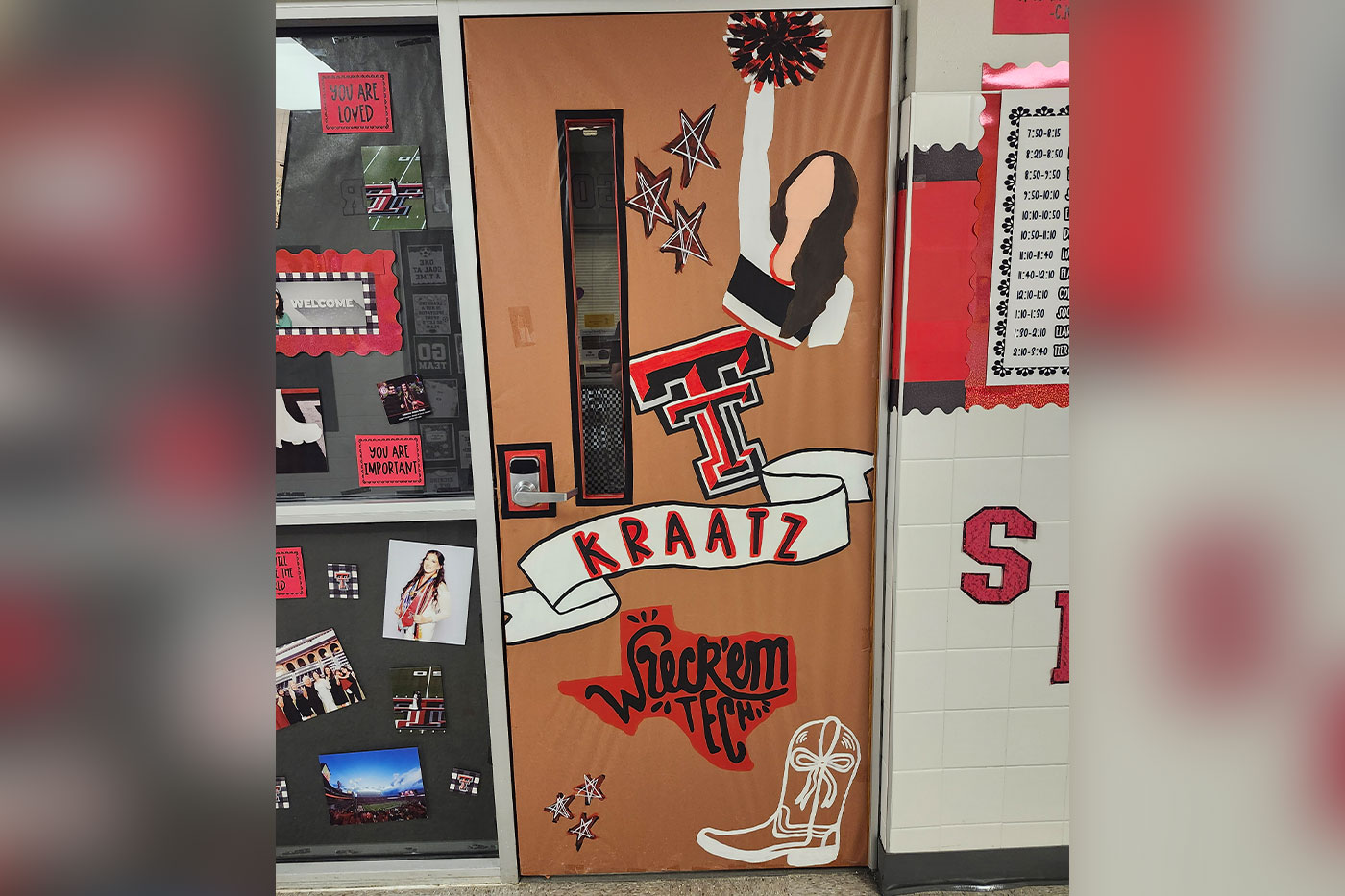 A classroom door is decorated with Texas Tech colors and symbols, including a cheerleader illustration, the Double T logo, the name “Kraatz,” “Wreck ’Em Tech” and a cowboy boot.