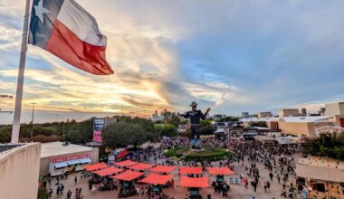 Overhead view of crowd at State Fair of Texas at Fair Park in Dallas, with Texas flag and Big Tex statue in background