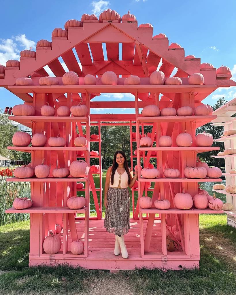 Image shows a woman posing in a vibrant-colored house at the Houston Pumpkin Festival. 