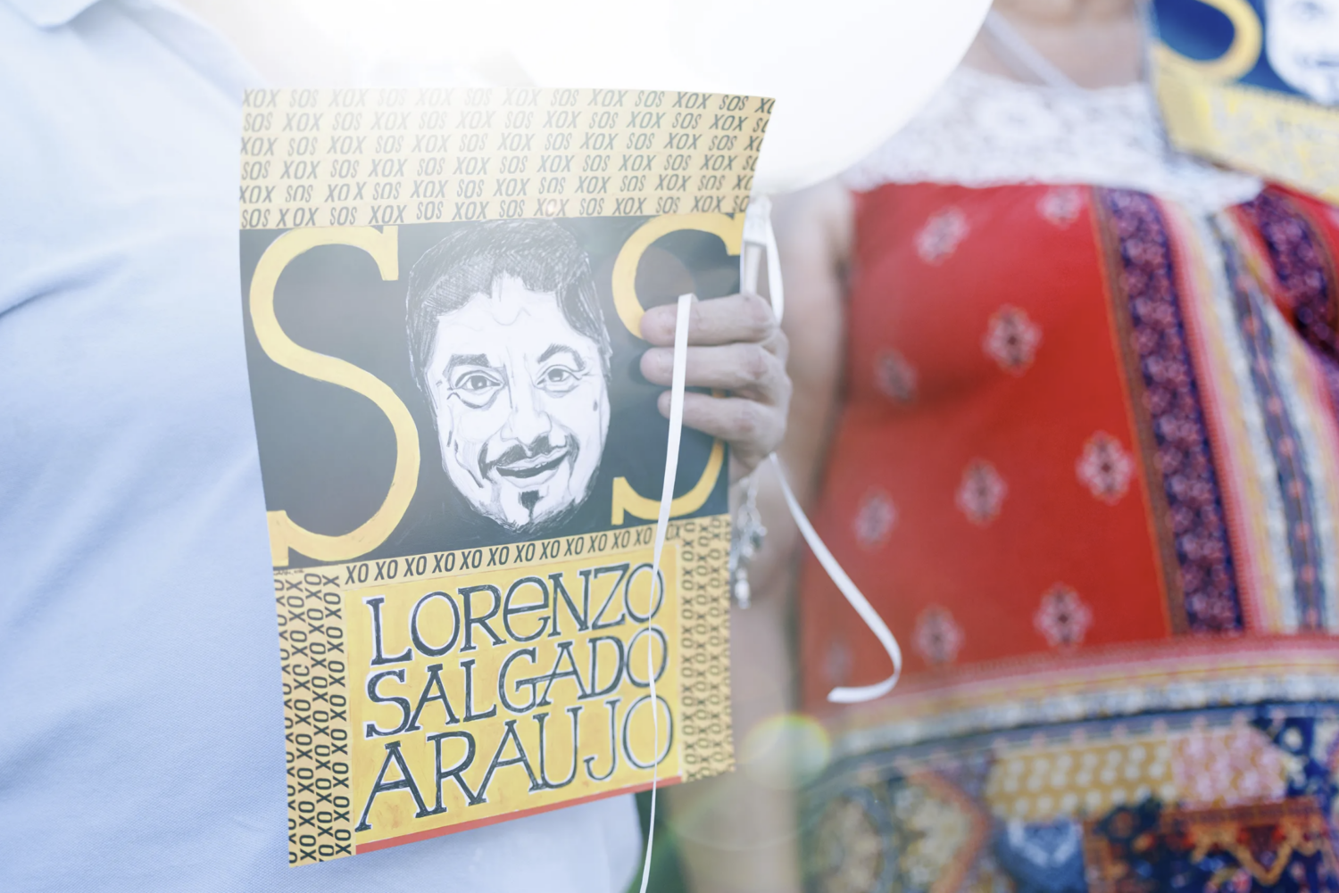 Vigil attendees hold up signs at a memorial for Lorenzo Salgado Araujo on the one month anniversary of his death, in Houston on Aug. 7, 2026.
