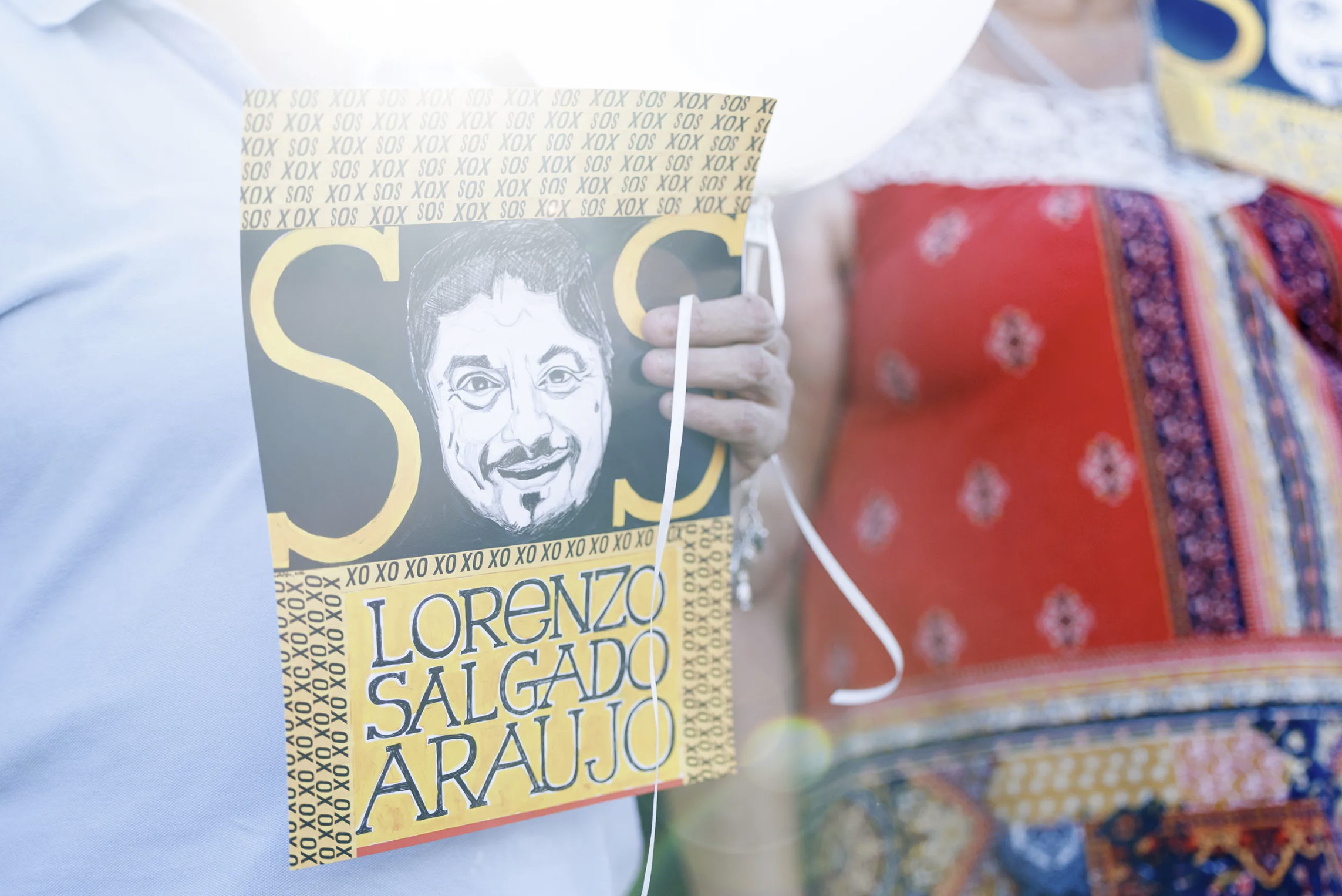 Vigil attendees hold up signs at a memorial for Lorenzo Salgado Araujo on the one month anniversary of his death, in Houston on Aug. 7, 2026.