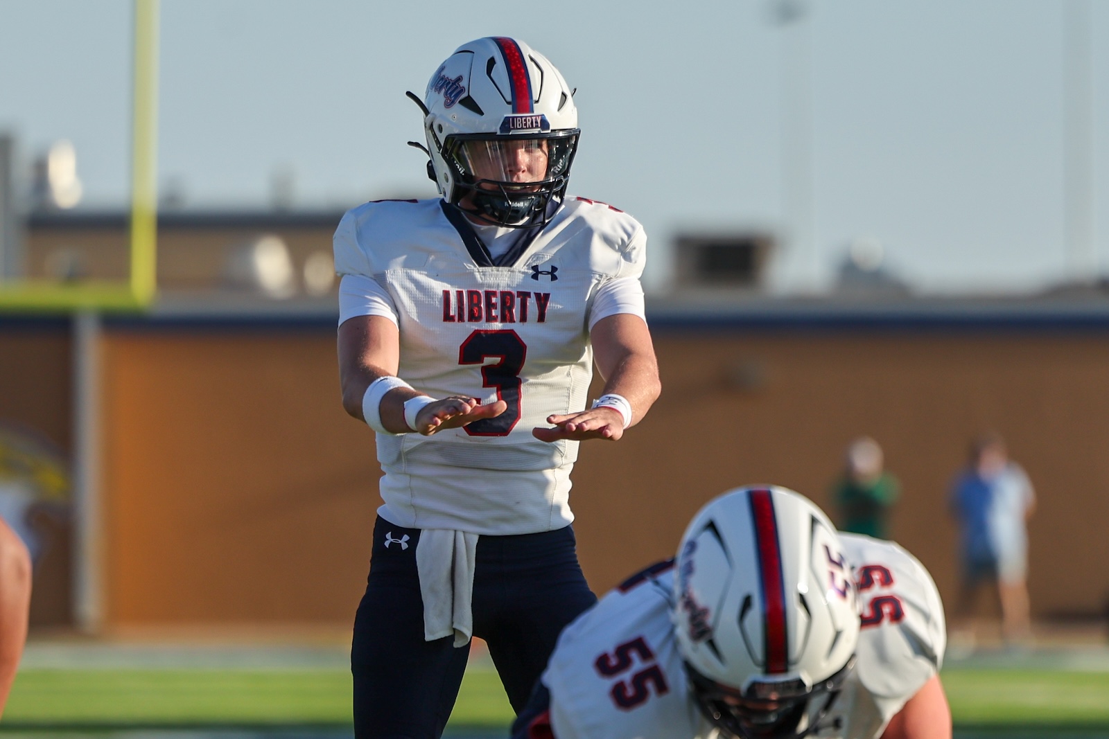 Football player wearing Liberty jersey #3 on the field, helmet on, preparing to block or tackle during a game.