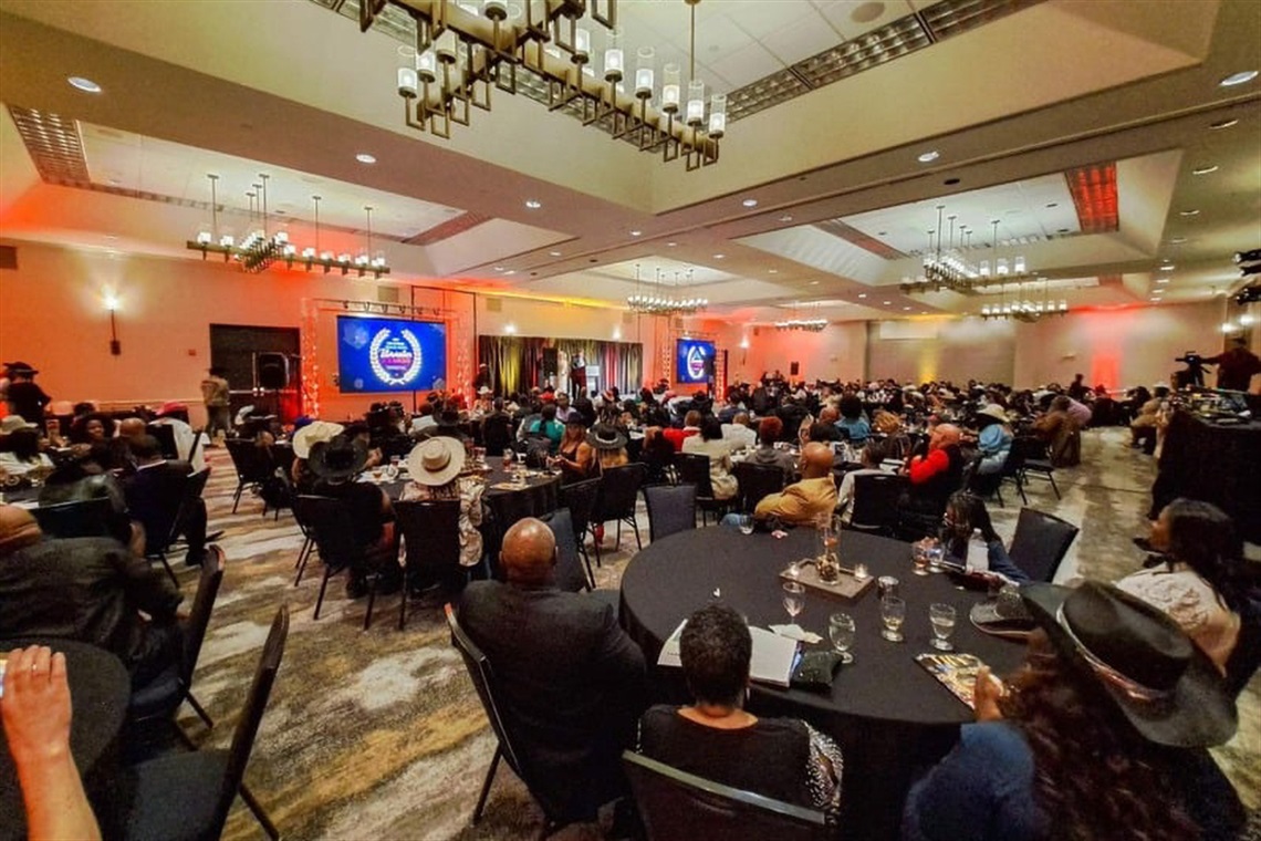 People seated around tables for award show banquet.