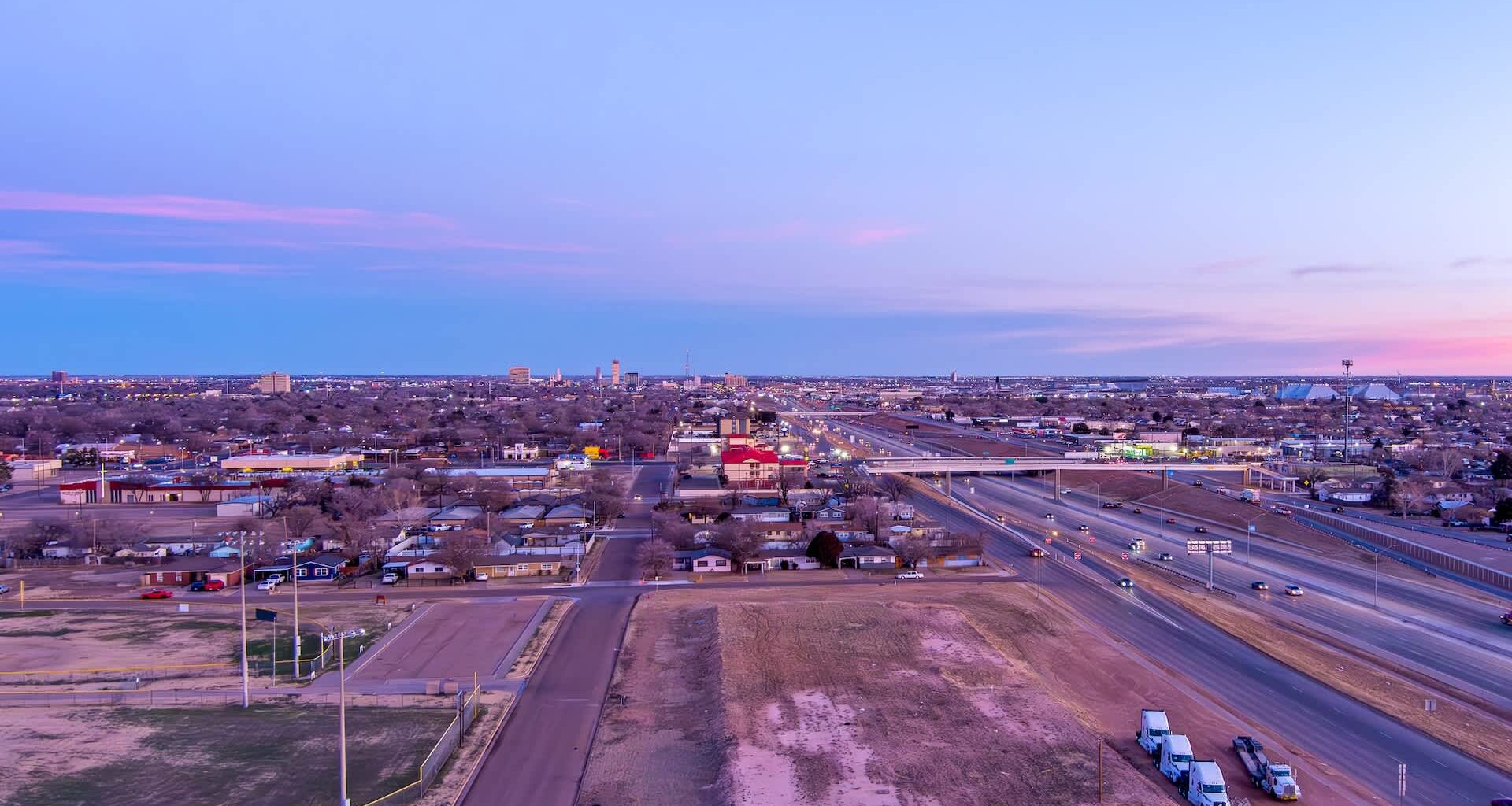 A view of Lubbock, Texas, with buildings, highways, and vehicles during twilight.