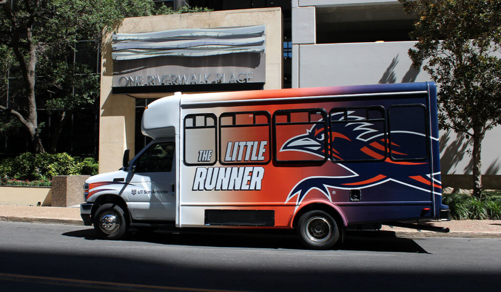 Red, white, and navy “The Little Runner" truck with a running roadrunner mascot graphic parked outside One Riverwalk Place.