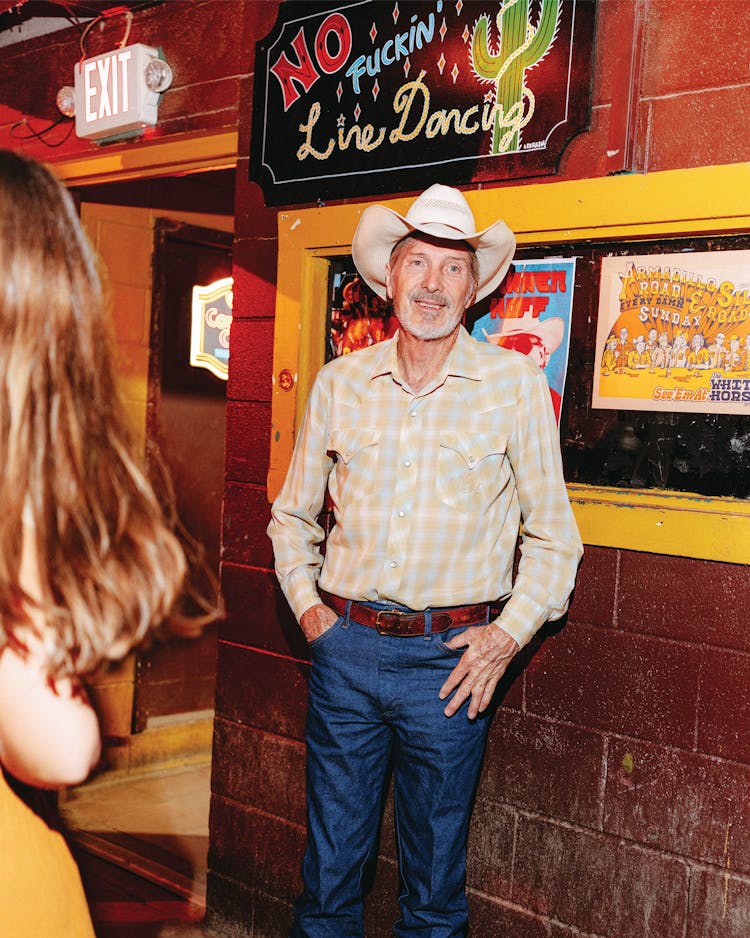 portrait of man under 'no fuckin' line dancing' sign