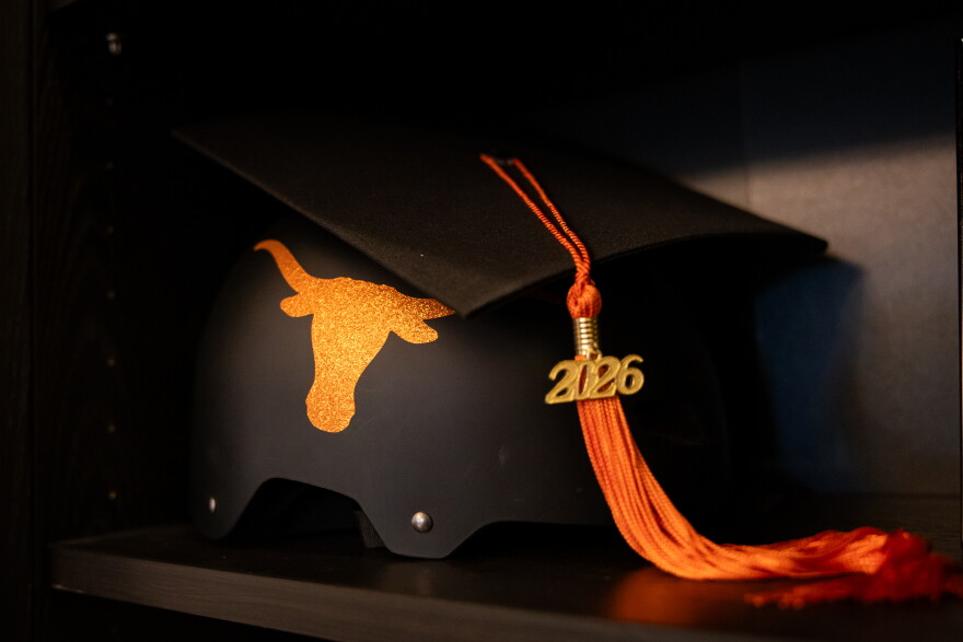 A helmet with an orange 'Longhorn' logo on it, and a graduation cap on top. The orange tassel on the cap features a "2026" attachment.
