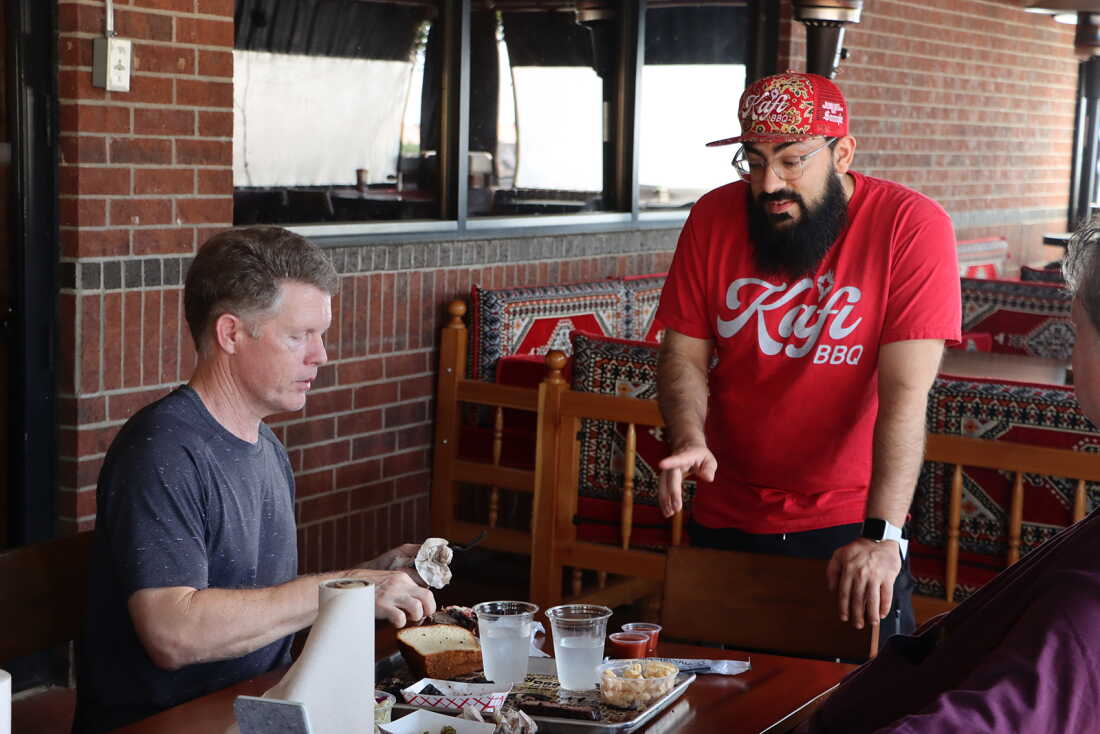 Kafi BBQ owner Salahodeen Abdul-Kafi, center, speaks with customer Johnathan Tate in Irving, Texas.