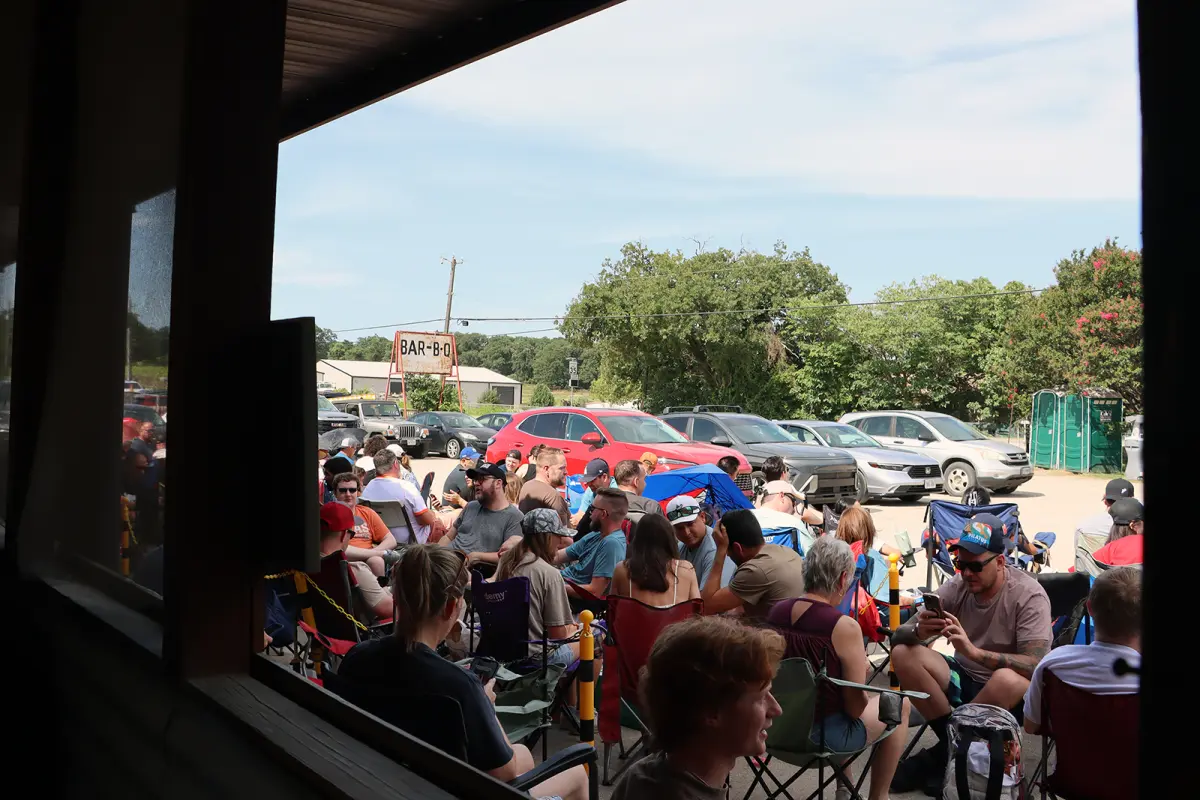 Customers sit in lawn chairs waiting for Goldee's BBQ to open on a summer Saturday in Fort Worth, Texas.